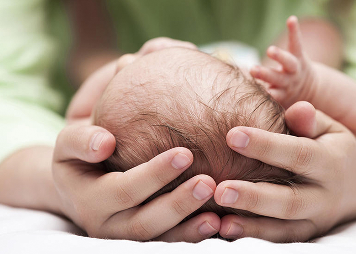 赤ちゃんの頭を両手で触っている写真｜不妊治療HP