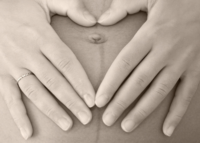 妊婦さんがお腹の上に手でハートを作っている写真｜不妊治療HP