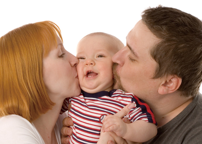 お父さんとお母さんが左右から可愛い赤ちゃんの頬にキスしているところ｜不妊治療HP