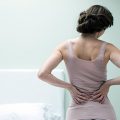 腰を抑えている女性の後ろ姿｜不妊治療HP